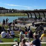 Crowd at an outdoor community event by the water
